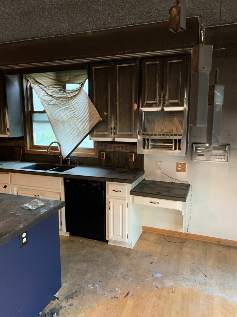 a kitchen with soot stained cabinets and soot on the floor and countertops