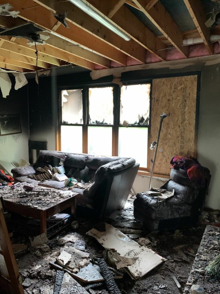 a living room with a couch and a table that has fire damage