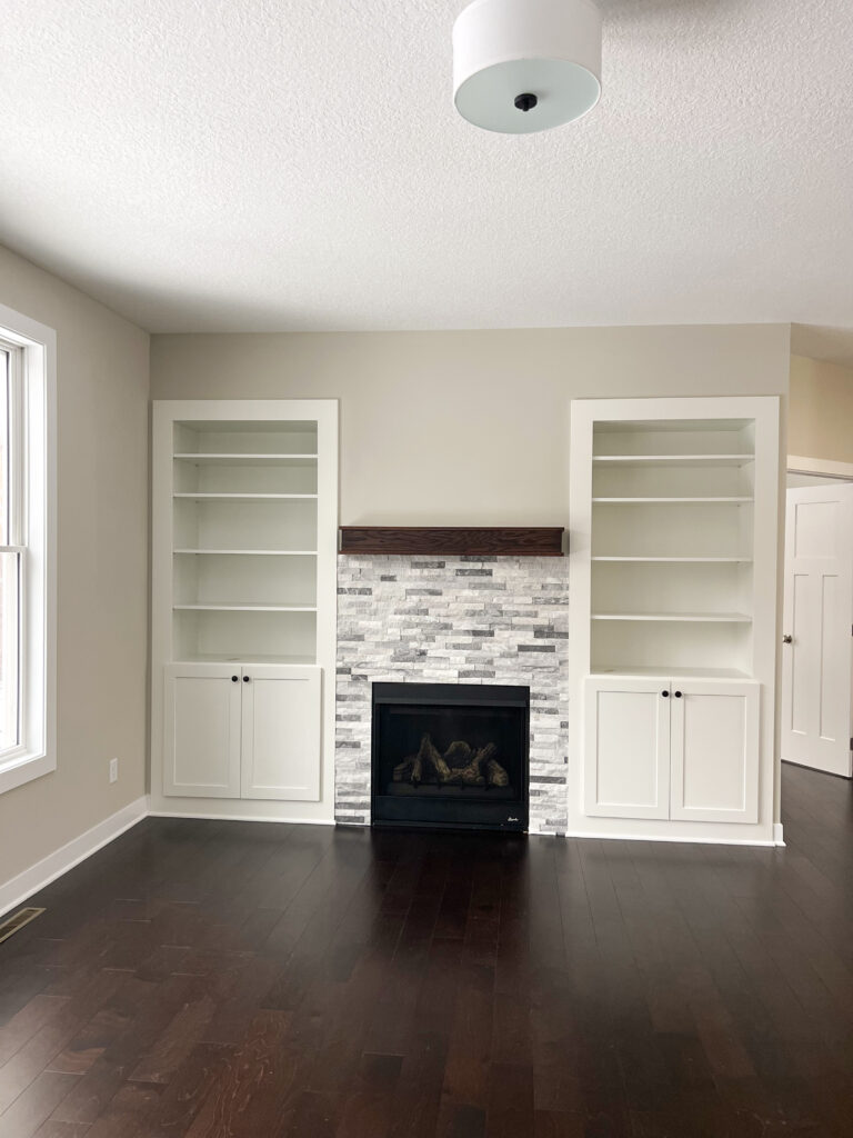 a fireplace in a room with white built in bookshelves