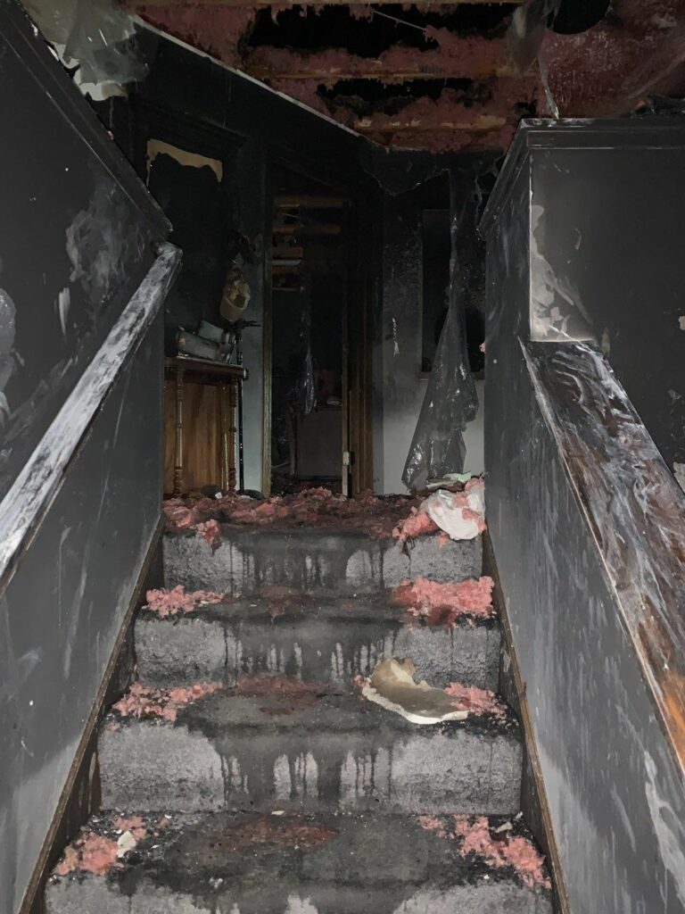 a fire damaged staircase with insultation debris on the stairs